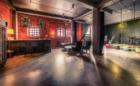 Арендовать Music loft (Мьюзик лофт). Лофт-пространство с кирпичными стенами, барной стойкой и высокими потолками. Черные стулья, кожаные диваны, музыкальная аппаратура, светильники, несколько окон. Основные цвета: красный, черный, серый. Таблички на стене, гладкий пол.