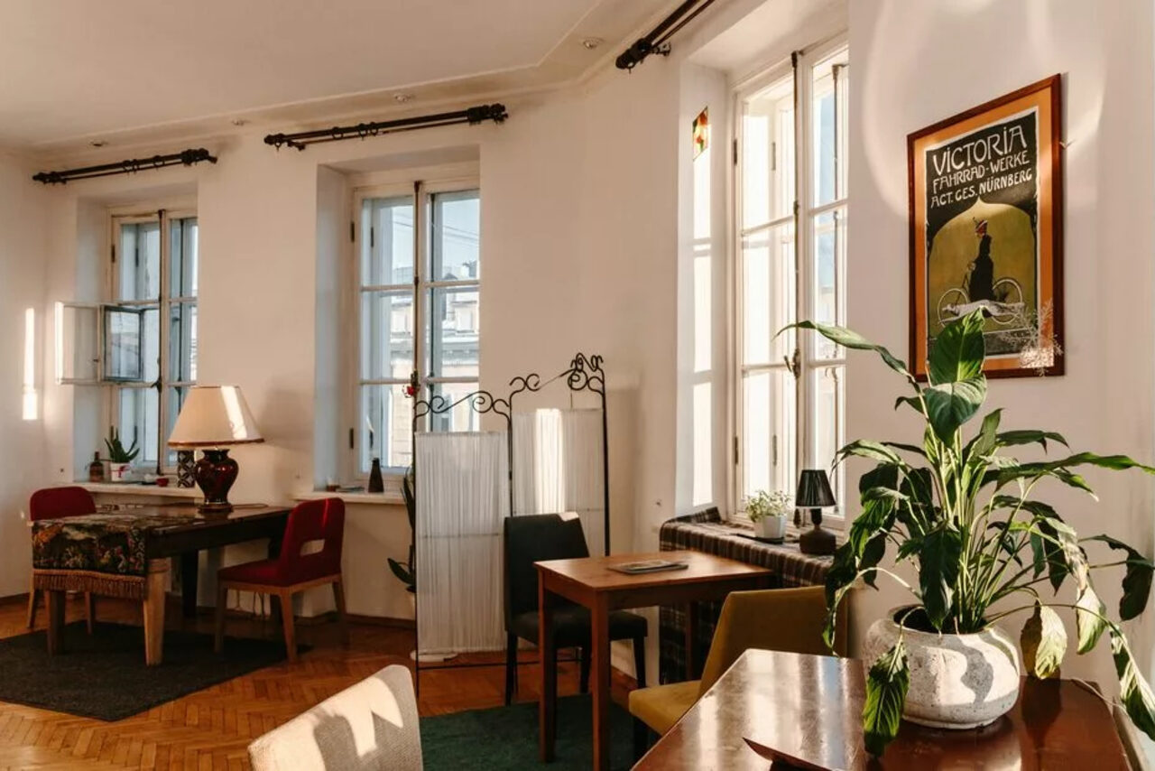 Арендовать Светлый лофт с панорамным видом. Большие окна. Столы с лампой и цветком, стулья