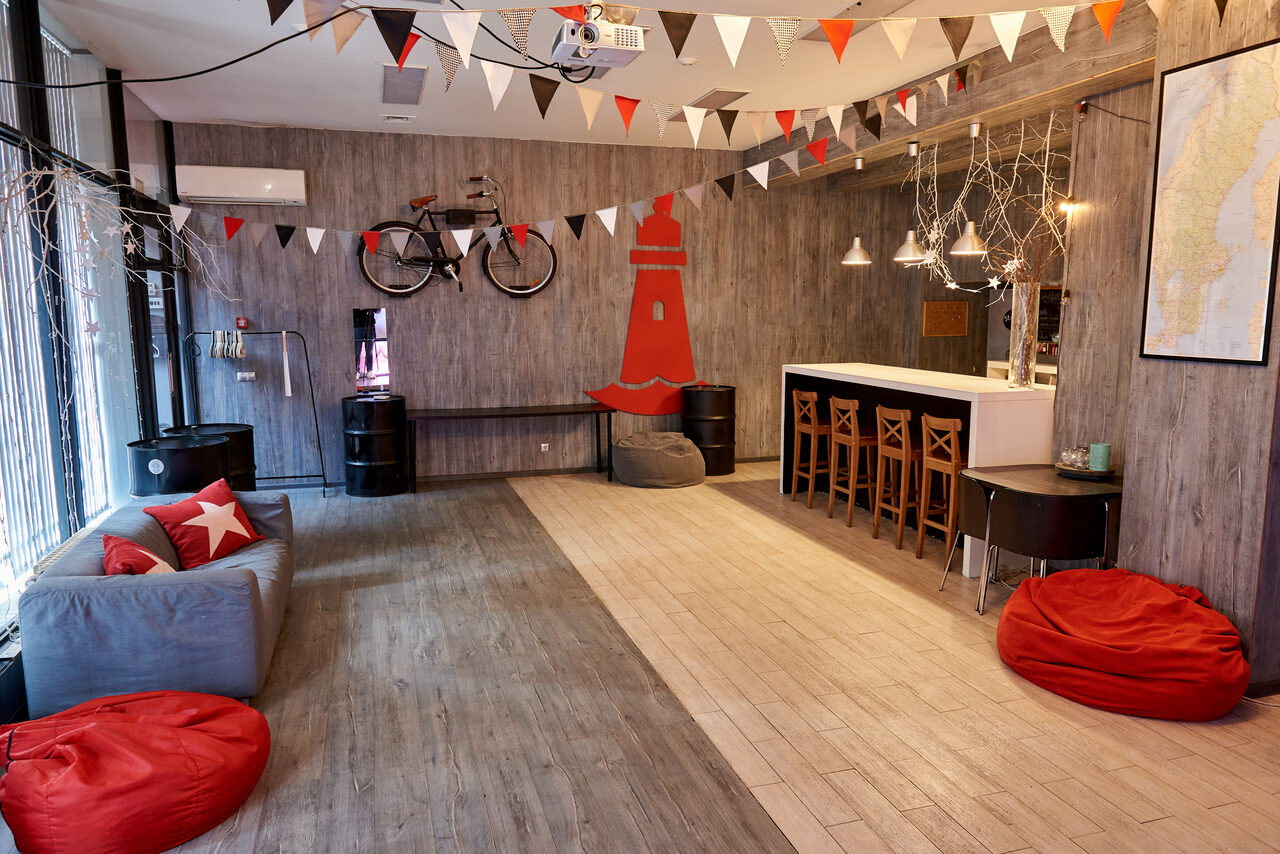 Арендовать Стильный лофт в скандинавском стиле. Вход с улицы. Красные пуфики, серое кресло.