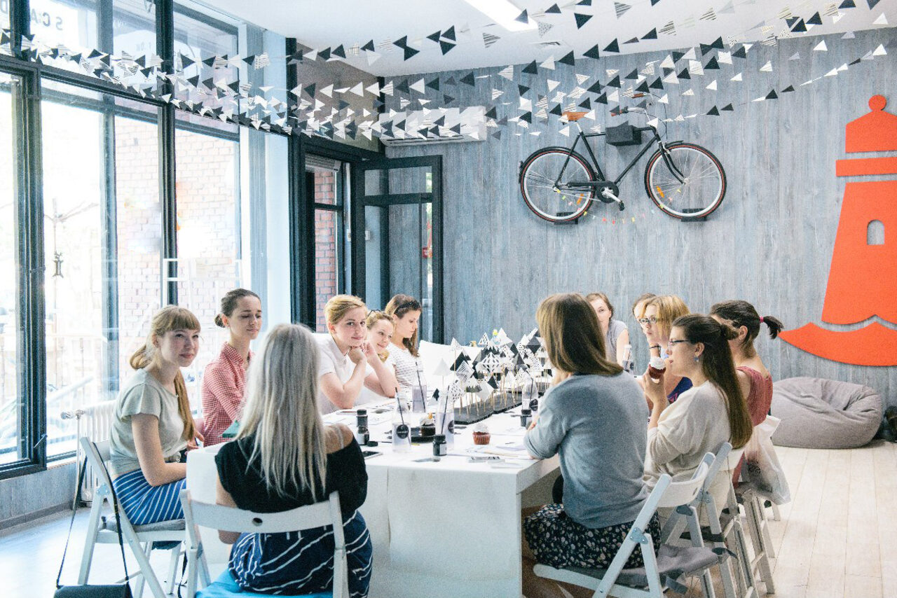 Арендовать Стильный лофт в скандинавском стиле. Вход с улицы. Девушки за общим столом в лофте на празднике. 