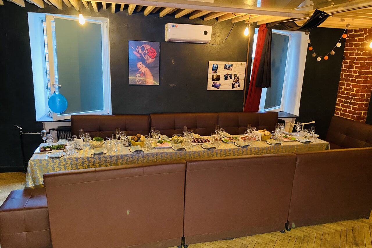 Арендовать Караоке-бар в центре города. Диваны с небольшими квадратными столами. Телевизор. Гирлянда