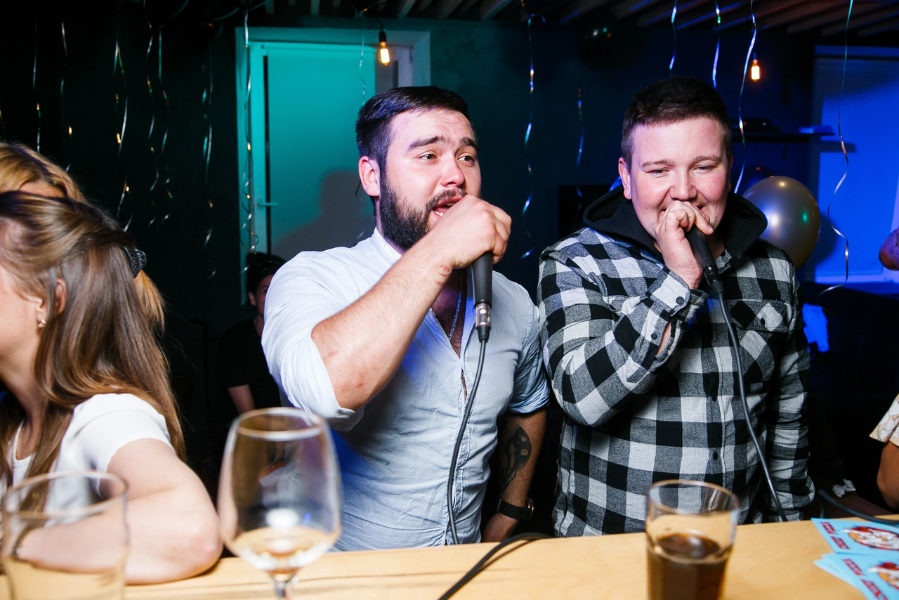 Арендовать Караоке-бар в центре города. Мужчина и девушка поют в караоке