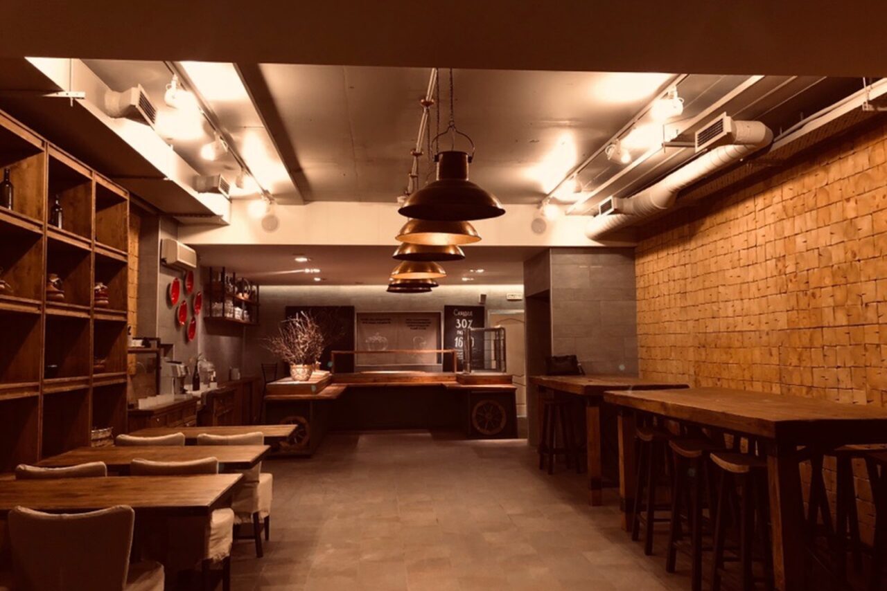 Арендовать Нора. Оборудованный зал. Свободное пространство. Высокие столы со стульями. Обычные столы со стульями