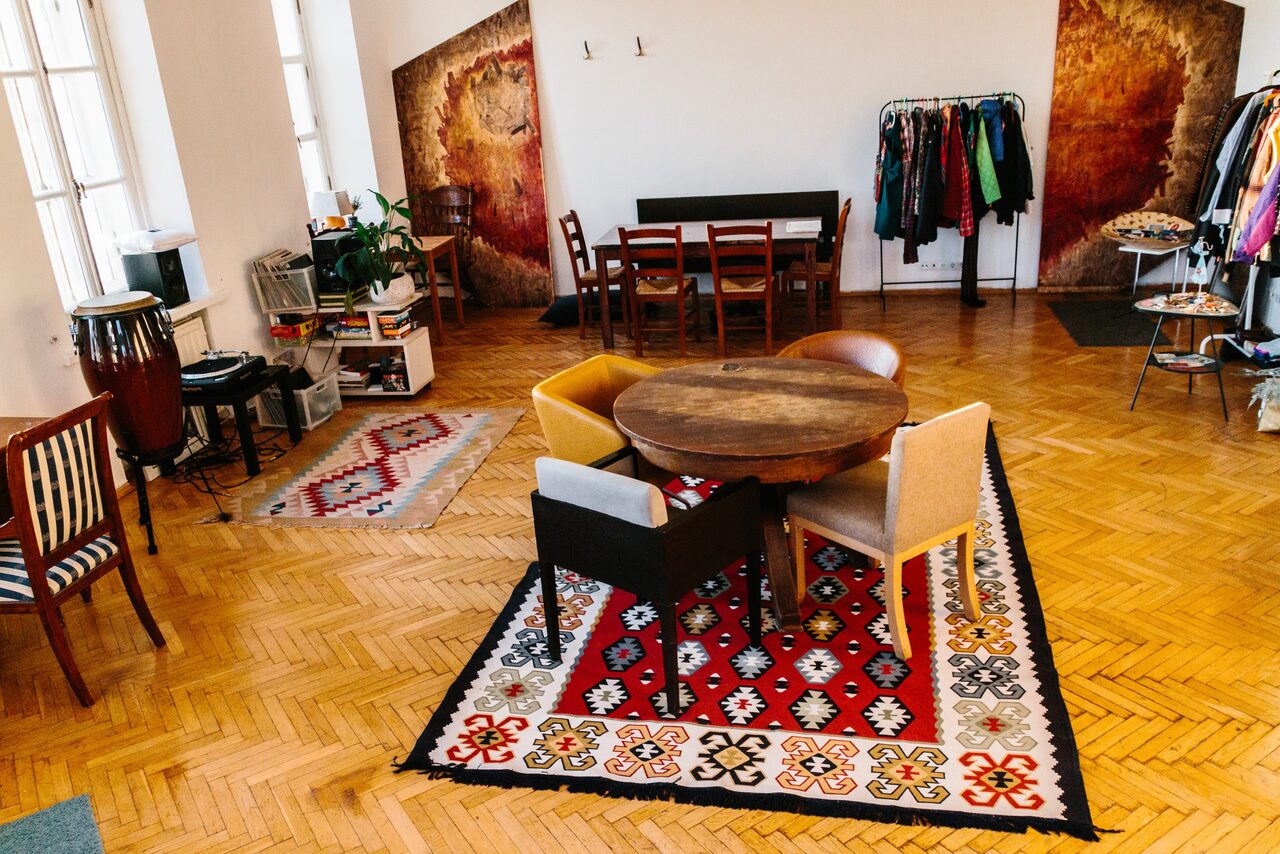 Арендовать Светлый лофт с панорамным видом. Столы со стульями. Ковры на полу. Различные элементы декора. Вешалки