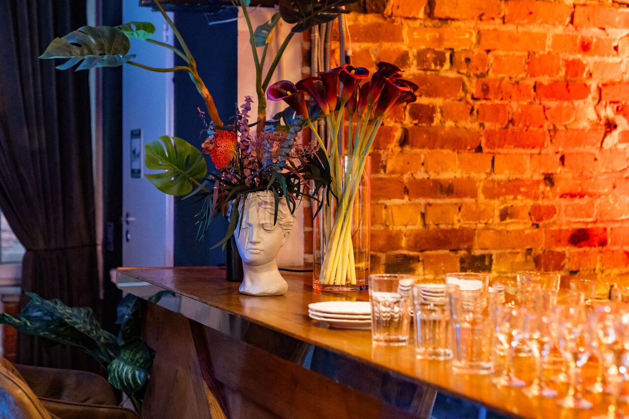 Арендовать Лофт со сценой. Широкая барная стойка с барными стульями. Стол с едой и посудой