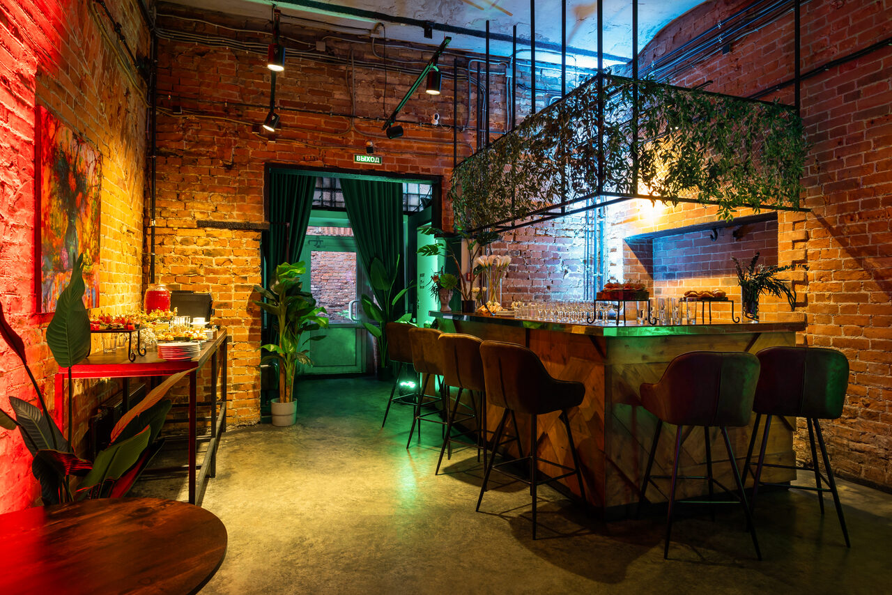 Арендовать Лофт со сценой. Накрытые большие круглые столы. Сцена с микрофоном и стулом. Большой экран