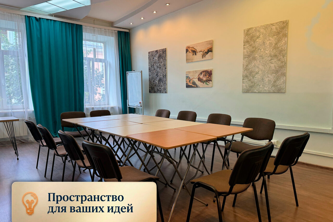 Арендовать Зал для мероприятий, тренингов, семинаров. Просторная комната с овальным столом из нескольких секций, окружённым стульями. Белая доска на треноге, за окнами зелень. Голубые шторы, три картины на белых стенах. Лампы в потолке. На картинке текст: «Пространство для ваших идей».