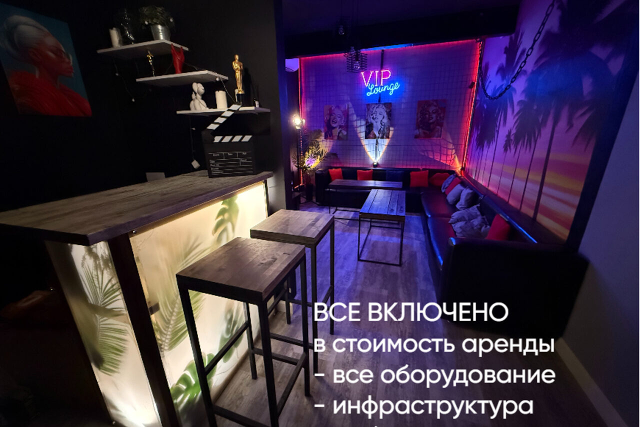 Арендовать Лофт ИЗНАНКА. Зал ГОЛЛИВУД. Караоке-зал с черными стенами и неоновым освещением. Барная стойка с высокими стульями, мягкие диваны у стен. На потолке прожекторы. Стены декорированы постерами и растительными узорами. Текст на фото: "ВСЕ ВКЛЮЧЕНО в стоимость аренды".