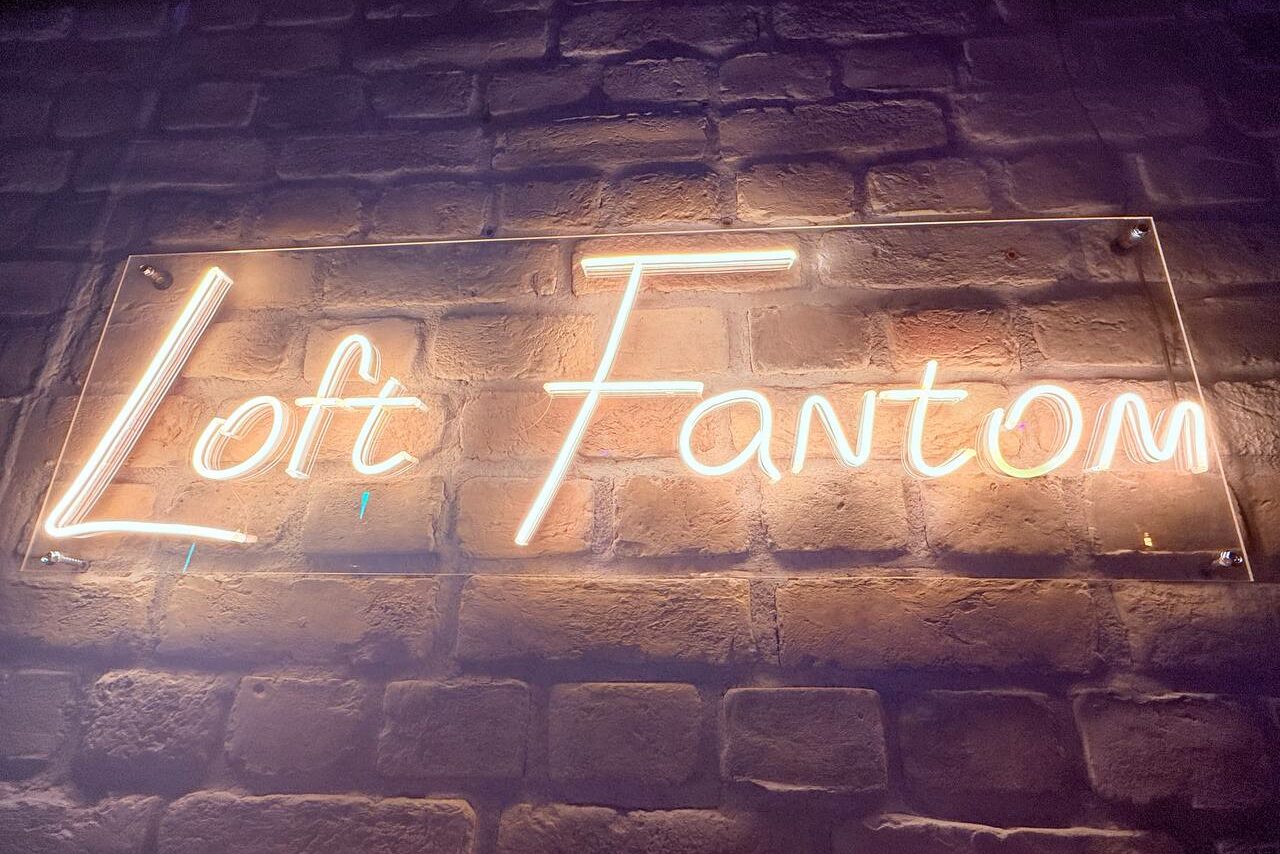 Арендовать Лофт Фантом. Неоновая вывеска с надписью "Loft Fantom" на стене из кирпичной кладки.