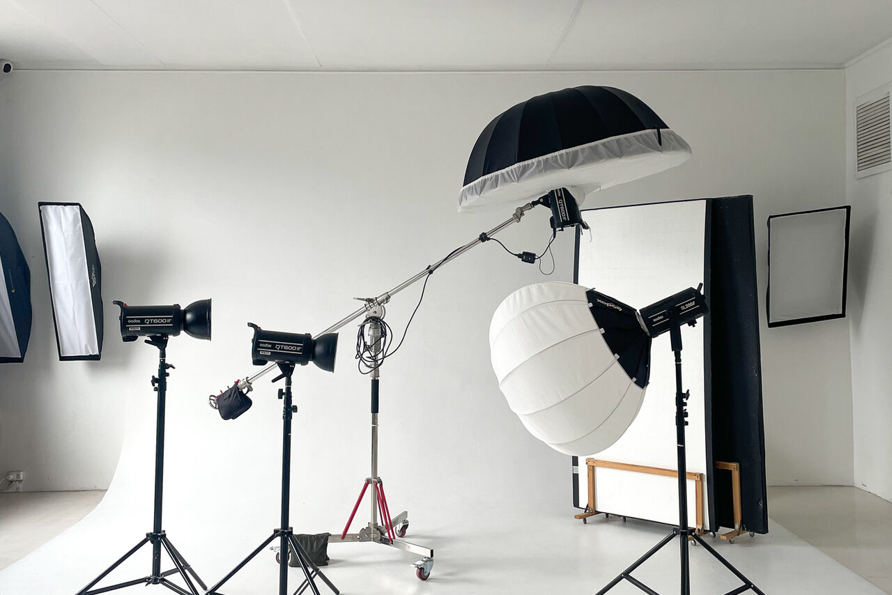 Арендовать Зал Серебро. Просторная и светлая фотостудия. Фотостудия с белыми стенами и потолком; студийное освещение: три профессиональных светильника на штативах, два софтбокса, два зонта. Фон белый, загнутый; отражатель; деревянная скамья. Освещение искусственное. Пространство чистое.