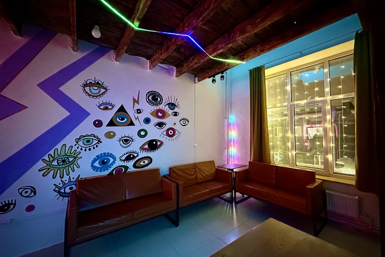 Арендовать Яркий двухуровневый лофт. Приглушённый свет. Диваны. Стена с рисунками. Окно со светящейся гирляндой