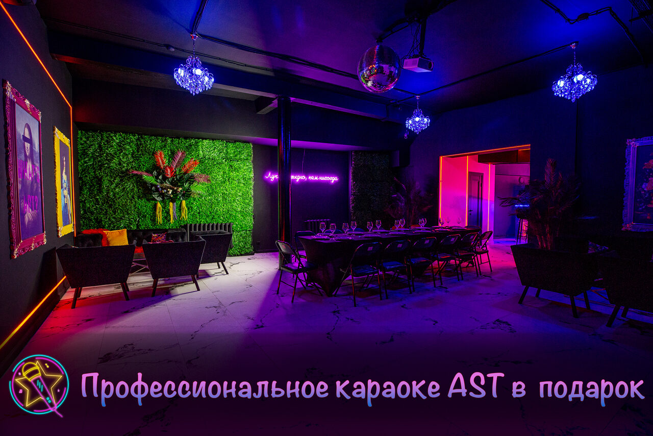 Арендовать Белый неоновый лофт-зал. Лофт-пространство с длинным столом и стульями, мягкие кресла, зелёная стена из растений, неоновая надпись, яркое освещение. Декор: люстры, диско-шар. Стены тёмные с картинами, на полу светлая поверхность. Текст на изображении: "Профессиональное караоке AST в подарок".