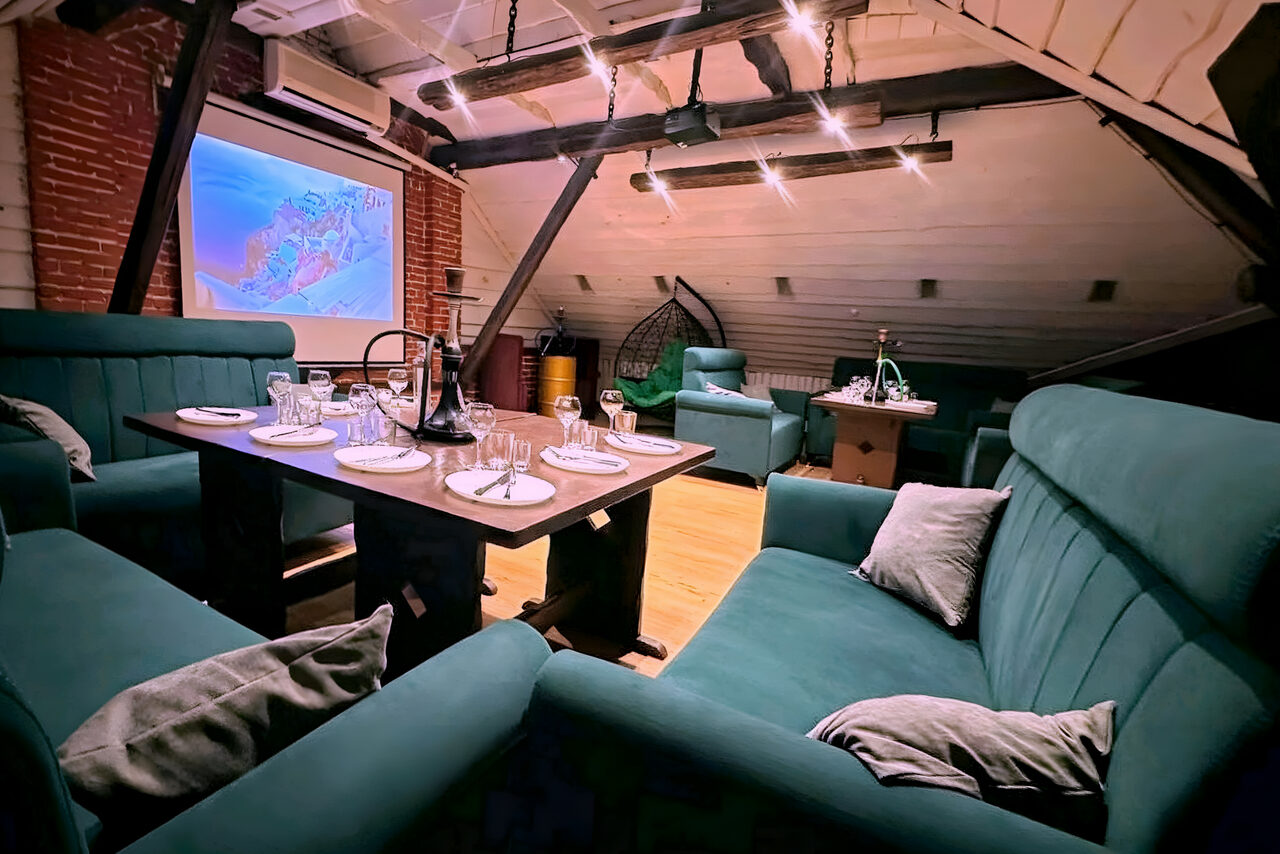 Арендовать Лофт-мансарда . Лофт с угловыми диванами, обеденным столом с сервировкой на шесть персон. Подвесной светильник, деревянные балки, кирпичная и деревянная обшивка стен. Экран или проектор на стене. Пастельные и древесные тона. Потолок с косыми линиями.