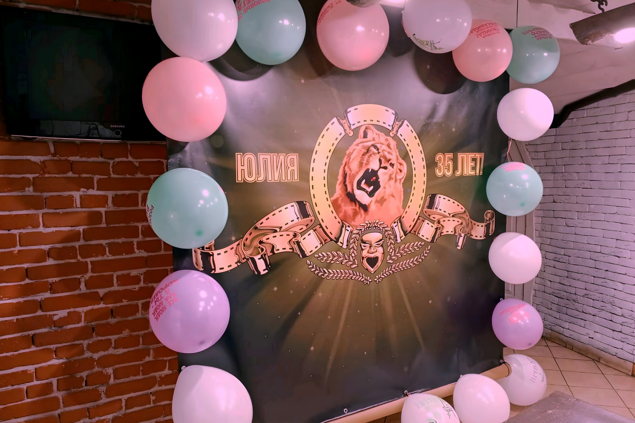 Арендовать Лофт-мансарда . Помещение с кирпичной стеной, на стене плакат с изображением льва и надписями «Юлия» и «35 лет», вокруг разноцветные воздушные шары. Светлые стены, подвесной потолок, плиточный пол.