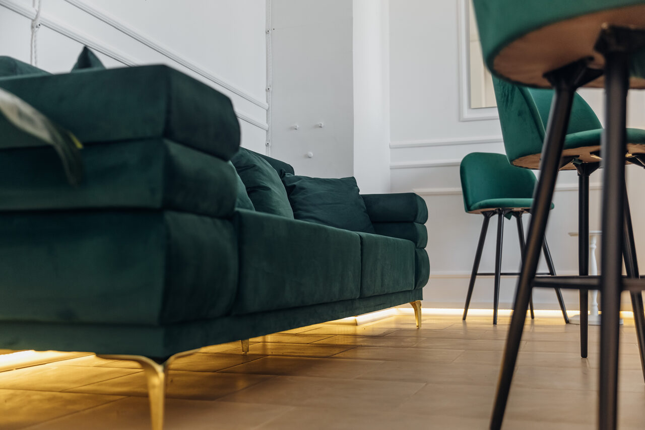 Арендовать Rubin Loft (Рубин Лофт). Зал Империал. Современное пространство с зелёным диваном и барными стульями, деревянный пол, белые стены, мягкое освещение снизу, элементы декора.