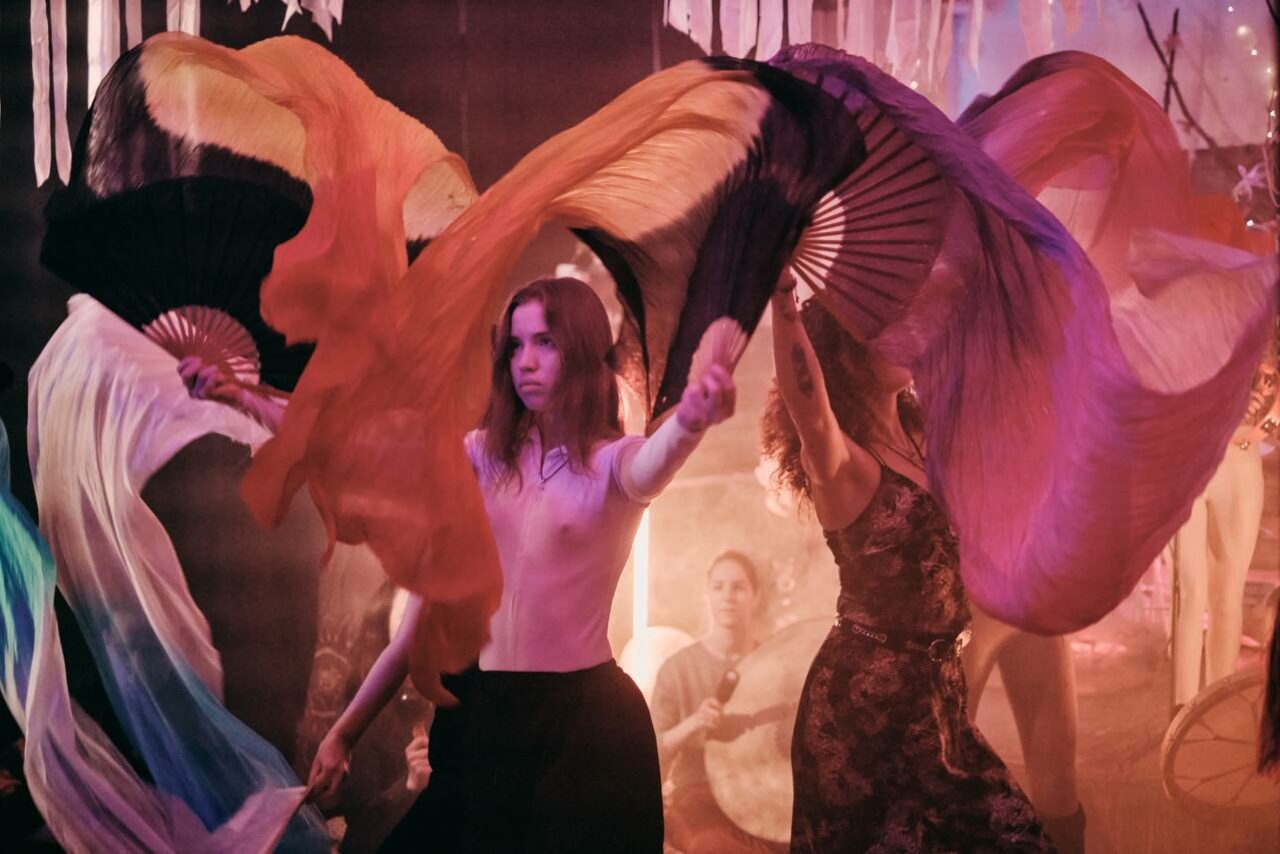 Арендовать Лес. Театральный лофт с верандой, сценой и вторым ярусом. Танцевальное помещение с низким освещением; люди танцуют с большими разноцветными шелковыми веерами; вокруг гирлянды и драпировки; мягкое розово-пурпурное освещение; место заполнено людьми.