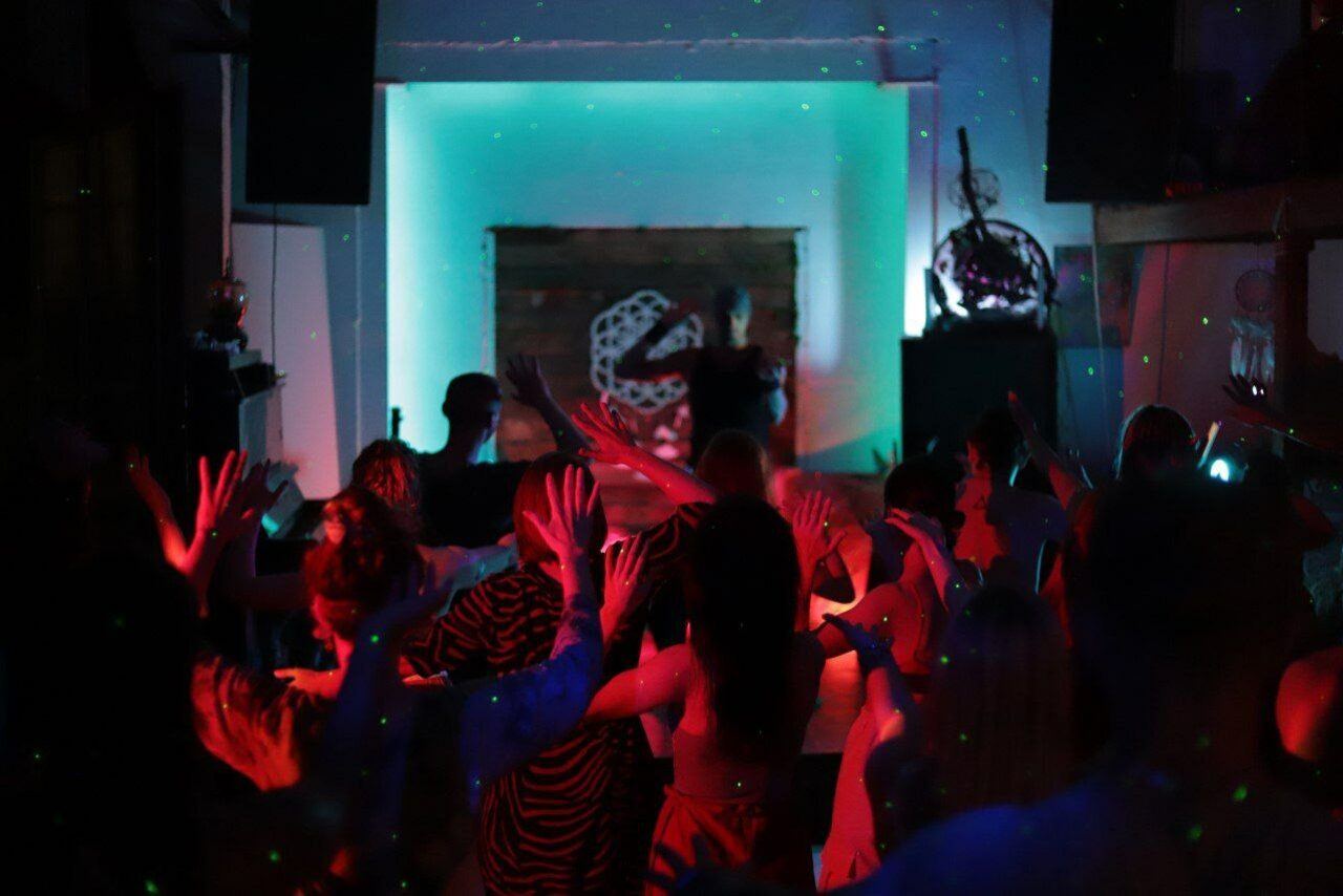 Арендовать Лес. Театральный лофт с верандой, сценой и вторым ярусом. Танцевальная площадка с людьми, яркое разноцветное освещение, проекционный экран на стене, темный интерьер. Колонки по периметру, украшение на стене, мягкие переходы световых эффектов.