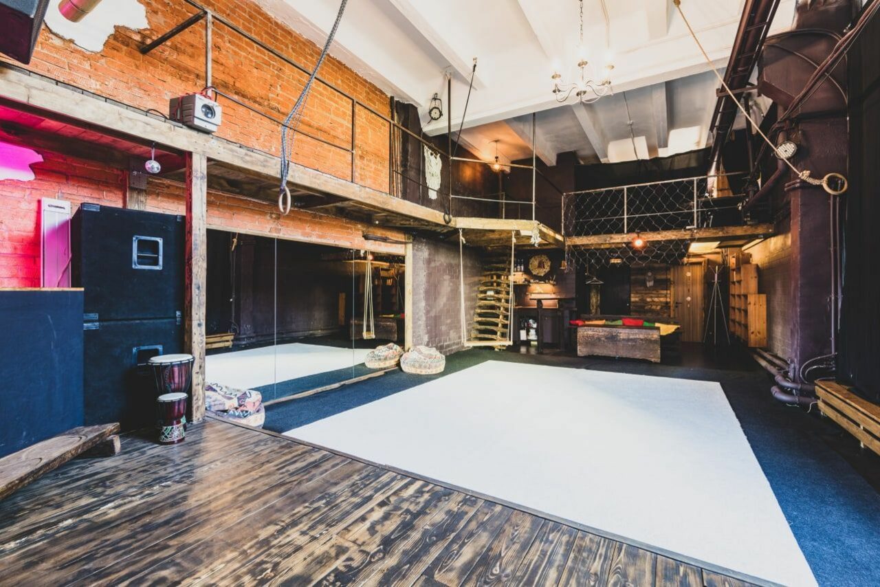 Арендовать Лес. Театральный лофт с верандой, сценой и вторым ярусом. Лофт-пространство с деревянными полами, открытыми кирпичными стенами, зеркалом, высоким потолком и антресолью. Мебель: мягкие пуфы, барабан, бильярдный стол. Освещение: потолочные светильники и лампы. Цвета: натуральные, красный акцент на стене.