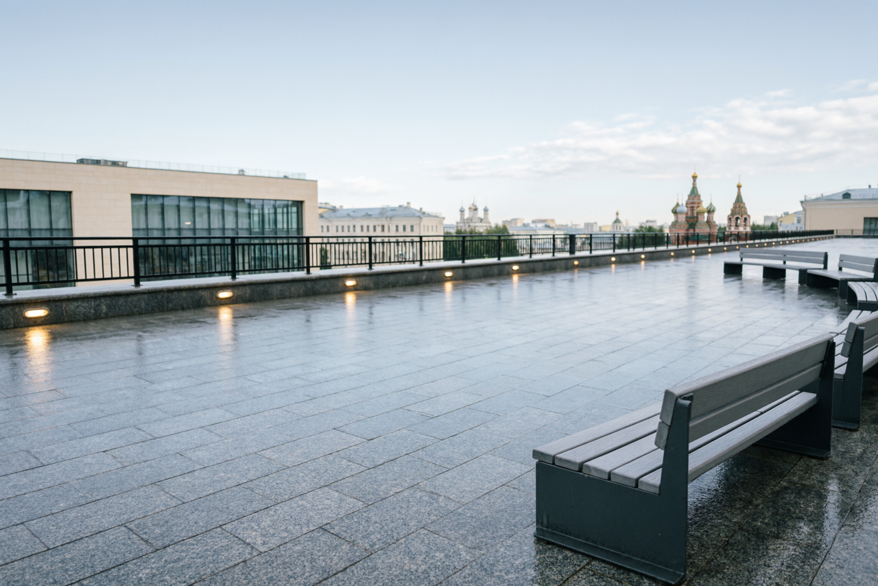Арендовать Площадка в Москве. Открытая терраса с видом на город, покрытая серыми плитами. По периметру установлены черные металлические перила. Расставлены деревянные скамейки с металлическими основаниями. Освещение встроено в опорную часть перил. Видны исторические здания.