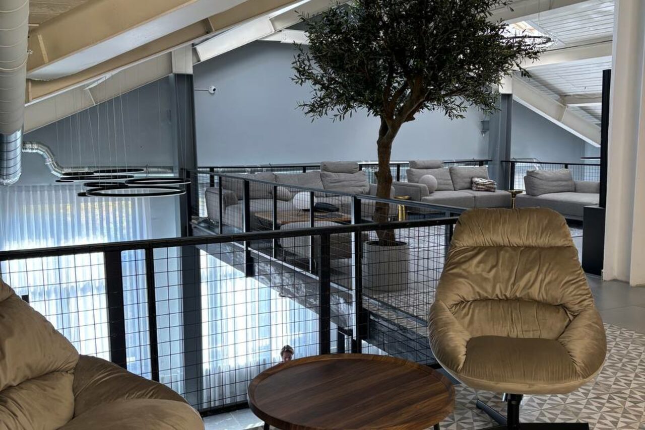 Арендовать Лофт Loftsinoby (Лофтсиноби)  для мероприятий. Современное пространство на втором этаже с деревянными и металлическими элементами. Мягкие кресла и диваны, журнальный столик. Высокие потолки, большое окно, искусственное дерево, подвесные светильники. Светло-серая цветовая гамма.