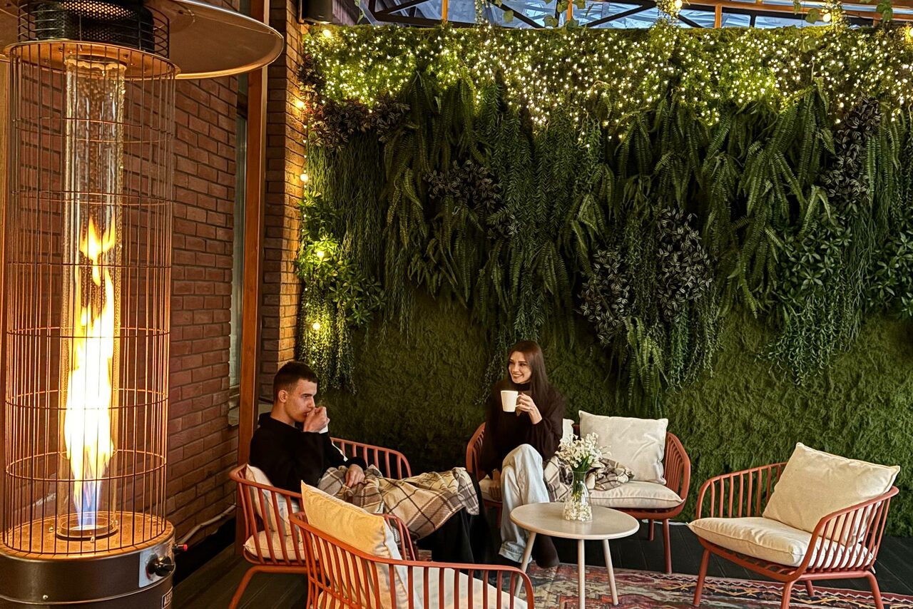 Арендовать Лофт Loftsinoby (Лофтсиноби)  для мероприятий. Открытое пространство с кирпичной стеной и живой зеленой стеной из растений. Металлическая мебель с подушками, круглый стол. Подвесные светодиодные огни. Газовая обогревательная лампа. Теплый декор с натуральными компонентами.