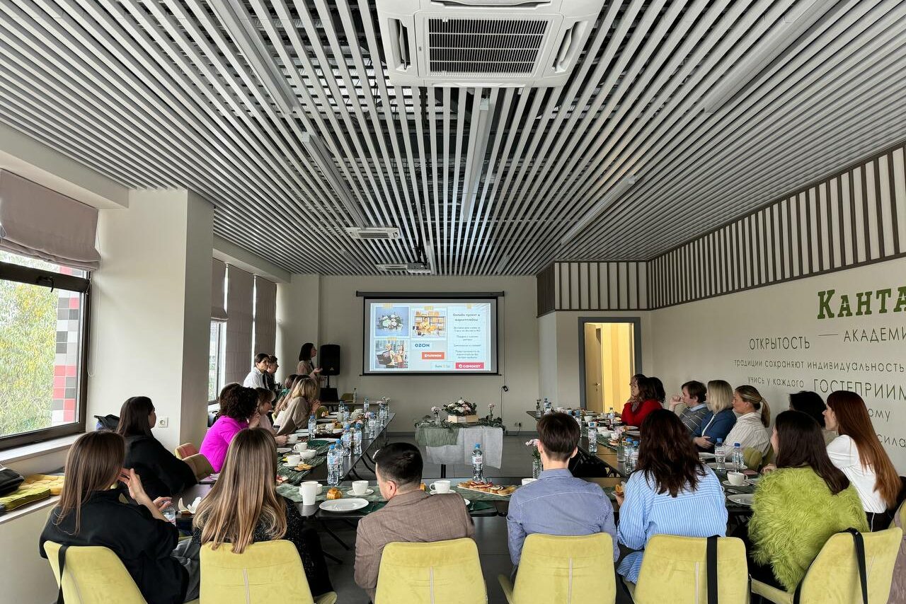 Арендовать Зал 6. Просторный и светлый конференц-зал до 50 человек в Академии Кантаты. Просторная конференц-комната с гладкими светлыми стенами и полосатым потолком. Центральный стол окружён жёлтыми стульями, на столе посуда и блокноты. На стене большой экран с презентацией, освещение естественное от окон слева.