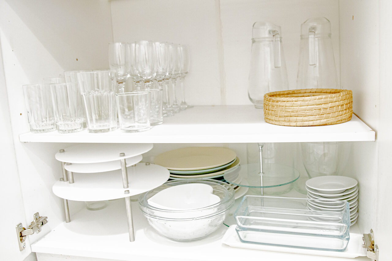 Арендовать Лофт Облака. Зал Баунти на Полярной. Белый шкаф с полками; верхняя полка: стеклянные бокалы и стаканы, кувшины, плетёная корзина; нижняя полка: стеклянные тарелки, миски, тарелки для пирожных, стеклянные блюда.