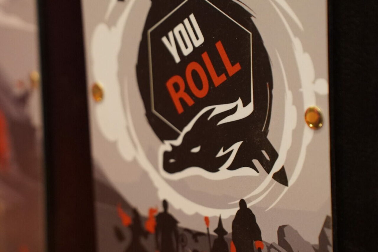 Арендовать YOU EVENT (Твой ивент). Клуб под закрытие. Постер с графическим изображением дракона и надписью "YOU ROLL" на фоне серых и чёрных силуэтов людей. Видны золотые крепления. Цвета: чёрный, серый, белый, оранжевый.