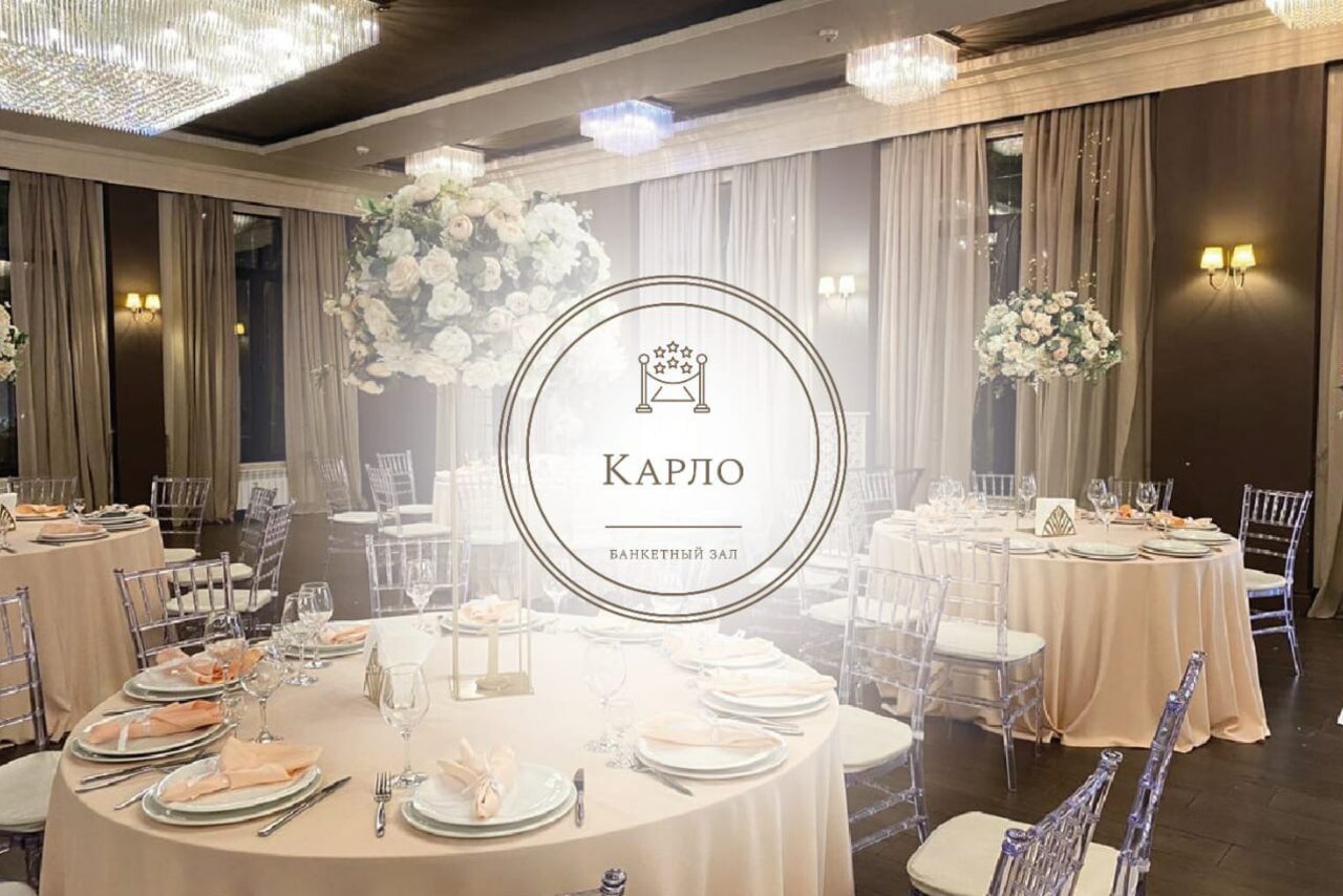 Арендовать Эдели. Просторный зал для мероприятий. Банкетный зал с круглыми столами, покрытыми белыми скатертями, сервированными тарелками и бокалами. Прозрачные стулья, высокие цветочные композиции, люстры и настенные светильники. Шторы в бежевых тонах, логотип и текст "Карло" на переднем плане.