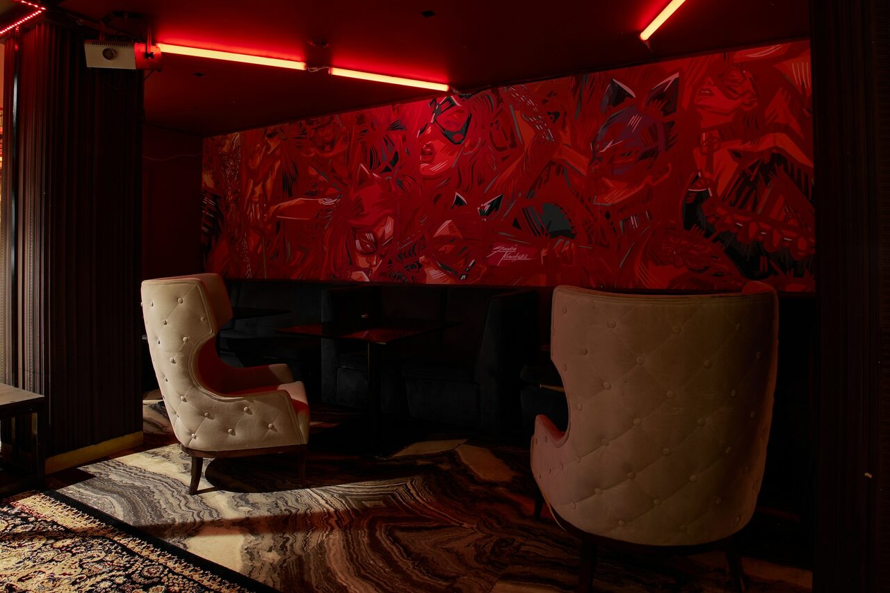 Арендовать Микс Afterparty(После вечеринки). Полутёмное пространство с красной неоновой подсветкой. Мягкие белые кресла, чёрные диваны, тёмные столы. Стены декорированы красной картиной с абстракциями, пол покрыт ковром с узором. На потолке красные светильники и камера наблюдения.