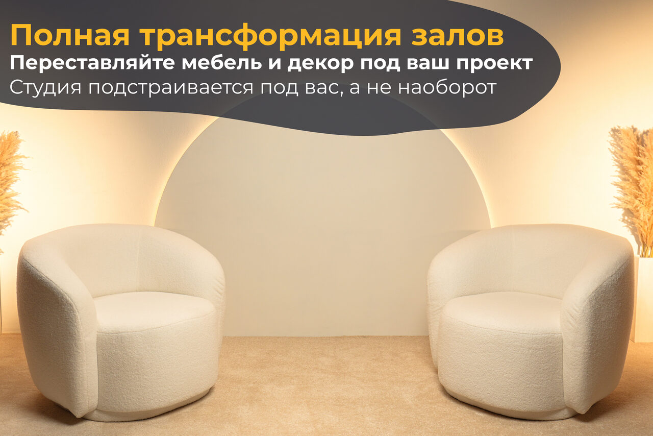 Арендовать Лофт Восторг. Пространство с двумя круглыми белыми креслами на бежевом ковре, фоновая стена с полукруглым элементом, бежевые оттенки, декор из сухих растений по бокам, мягкое освещение, текст на стене.