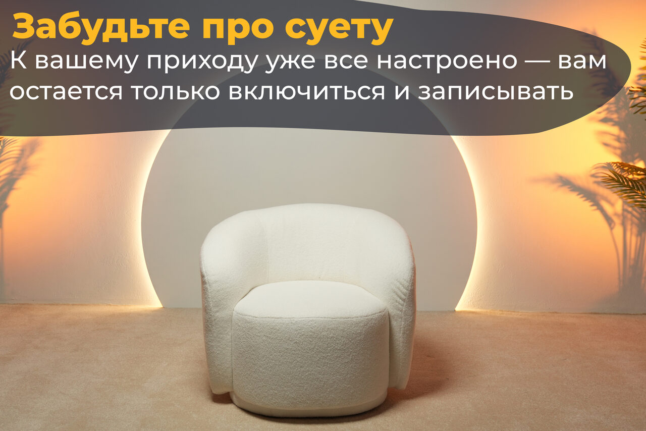 Арендовать Лофт Восторг. Пространство с мягким креслом и пуфом на бежевом ковре. Светлые стены, боковая подсветка с эффектом солнца, декоративные растения. Верхний текст: "Забудьте про суету", нижний текст: "К вашему приходу уже все настроено — вам остается только включиться и записывать".