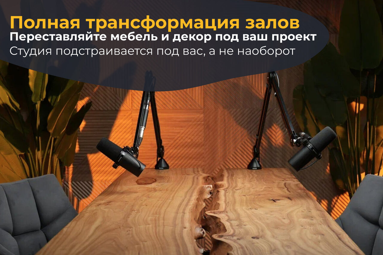 Арендовать Лофт  Эйфория. Пространство со столом из светлого дерева, двумя микрофонами на стойках, серыми креслами и растениями на заднем плане. Стена оформлена деревообразной текстурой. Текст: "Полная трансформация залов. Переставляйте мебель и декор под ваш проект. Студия подстраивается под вас, а не наоборот".