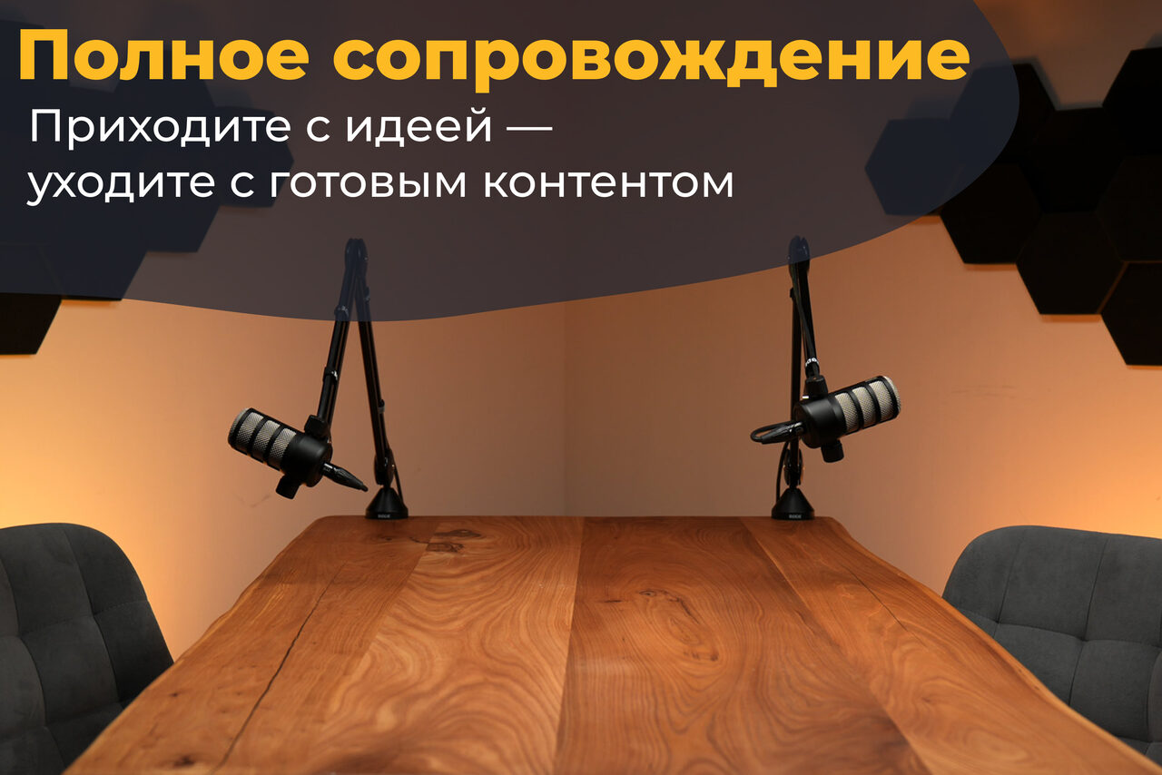 Арендовать Лофт Позитив. Студия с деревянным столом, двумя микрофонами на стойках, серыми креслами и оранжевым освещением. На стене черные акустические панели. Наверху текст: «Полное сопровождение. Приходите с идеей — уходите с готовым контентом».