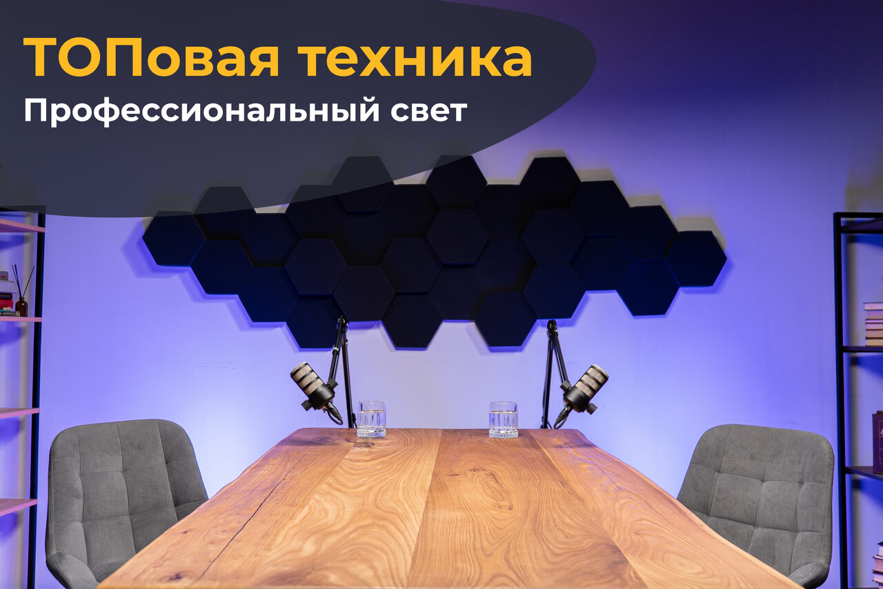 Арендовать Лофт Позитив. Таблица из светлого дерева в центре комнаты, по сторонам серые кресла. На столе два микрофона, два стеклянных стакана. На заднем плане чёрные шестиугольные панели на фиолетовой стене. Справа книжная полка. Освещение направленное. Текст: "ТОПовая техника, Профессиональный свет".