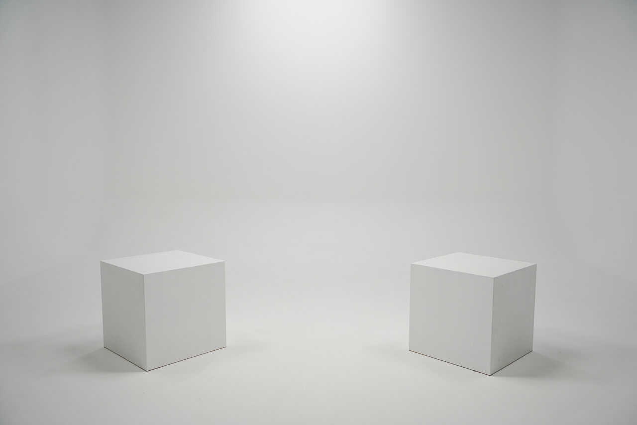 Арендовать Лофт Циклорама. Белое помещение с минималистичным дизайном. Два белых кубических стула или подиума стоят рядом друг с другом. Равномерное студийное освещение, гладкие стены и пол. Цветовая гамма полностью белая.