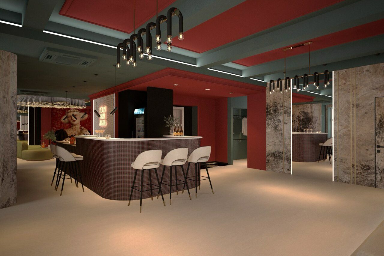 Арендовать Стильное пространство Астрид. Угловой бар с белой стойкой и пятью высокими белыми стульями с черными ножками. На потолке подвесные светильники с лампами накаливания, стены бордовые и серые с зеркалами. На заднем плане полки с напитками. Потолок синие и красные панели.