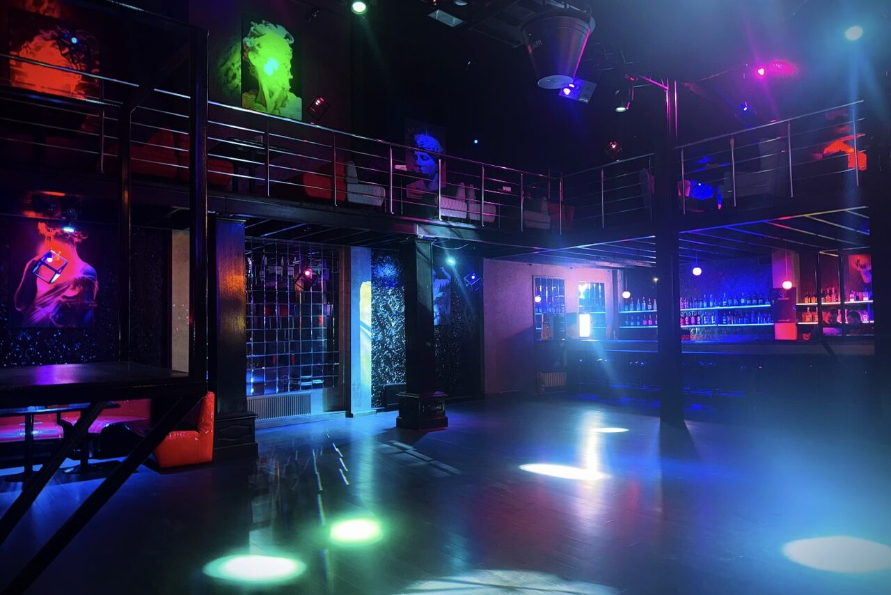 Арендовать Castle Concert Hall(Концертный зал Замок). Ночной клуб с двухуровневой планировкой, множеством разноцветных неоновых огней. Металлические перила, барная стойка, высокие потолки, черные стены. Декор из светящихся панелей, открытая площадка для танцев.