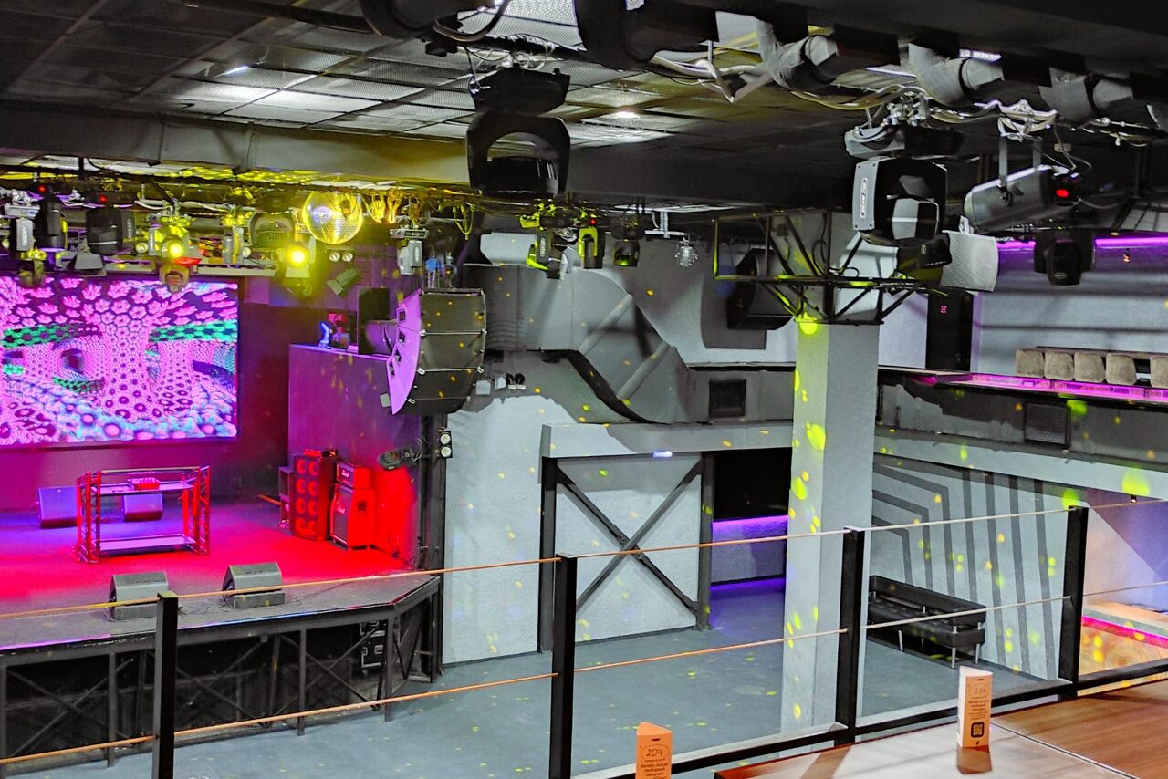 Арендовать PRAVDA(Правда). Просторный зал на 800 гостей. Концертный зал с большим экраном на стене, DJ-стойкой и световым оборудованием. Серые стены, черный потолок с видимыми коммуникациями, разноцветные прожекторы. Танцпол с ограждением, балкон с барными стойками. Пространство в индустриальном стиле.