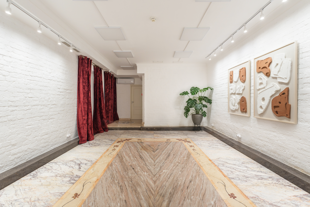 Арендовать Светлый Лофт. Прямоугольное помещение с белыми кирпичными стенами, красными шторами, мраморным полом, точечным освещением. На стене подвешены абстрактные картины. В углу стоит зеленое растение в сером горшке.