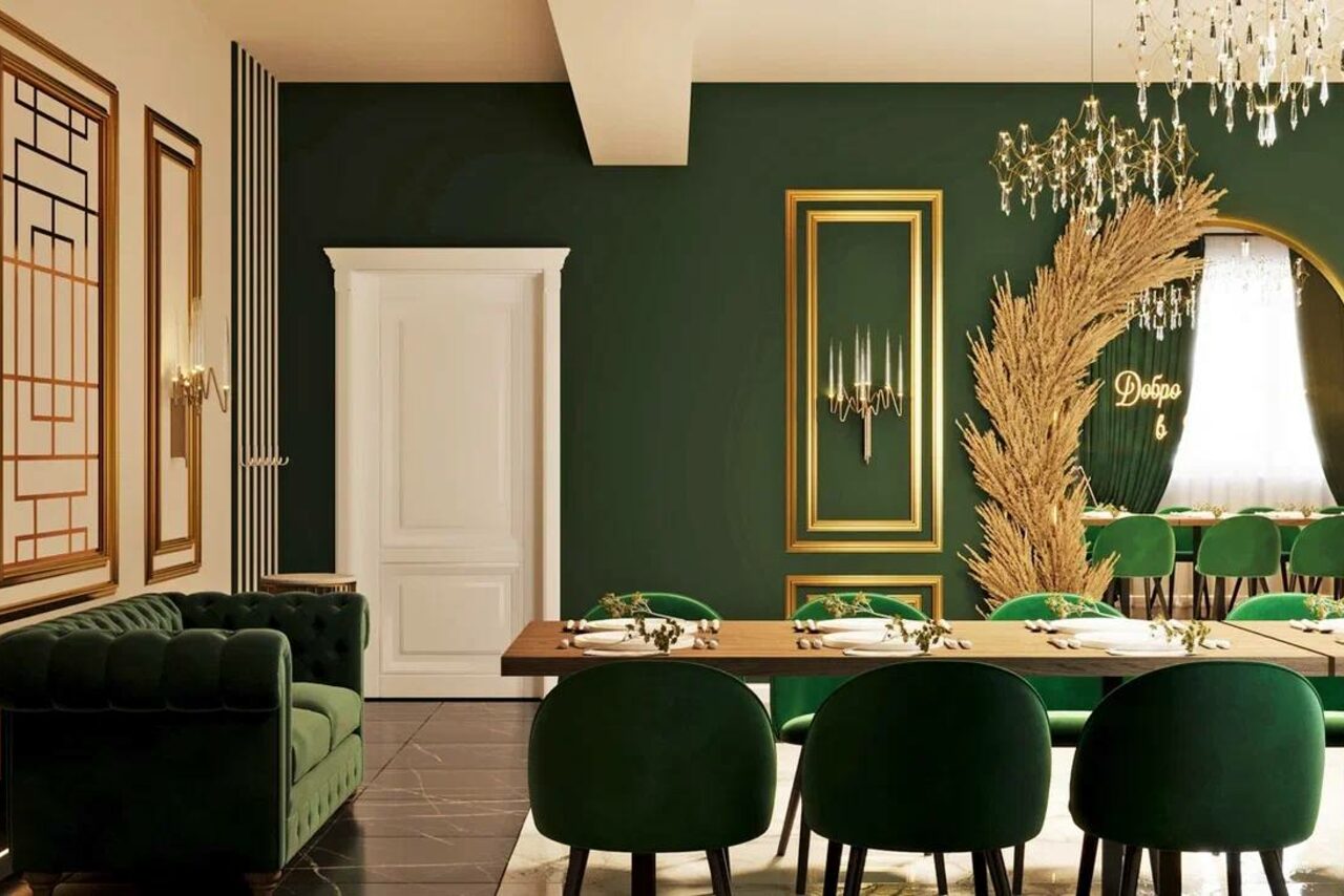 Арендовать Голливуд. Элегантный лофт в зелено-бежевых оттенках. Зал с тёмно-зелёными стенами, декорированными золотыми рамками. Длинный деревянный стол с зелёными стульями, на столе посуда и салфетки. Зелёный диван в углу. Люстра с подвесками, декоративное растение, белая дверь, текст «Добро».