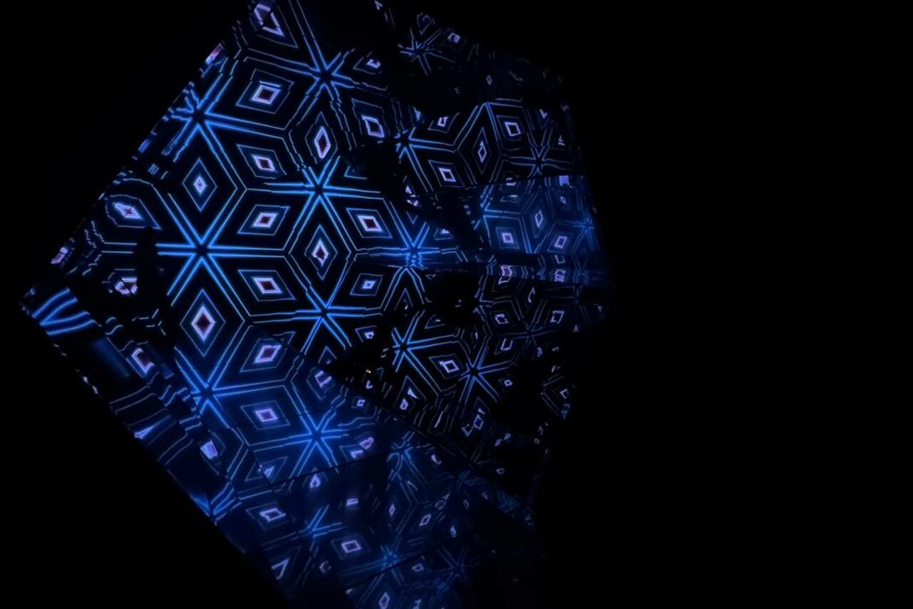 Арендовать Futurione(Футурио́не). Тёмное пространство с LED-панелями, создающими геометрический узор в тёмно-синих и чёрных цветах. Узоры ромбовидной формы с динамическим освещением, отражающимся на гладкой поверхности.