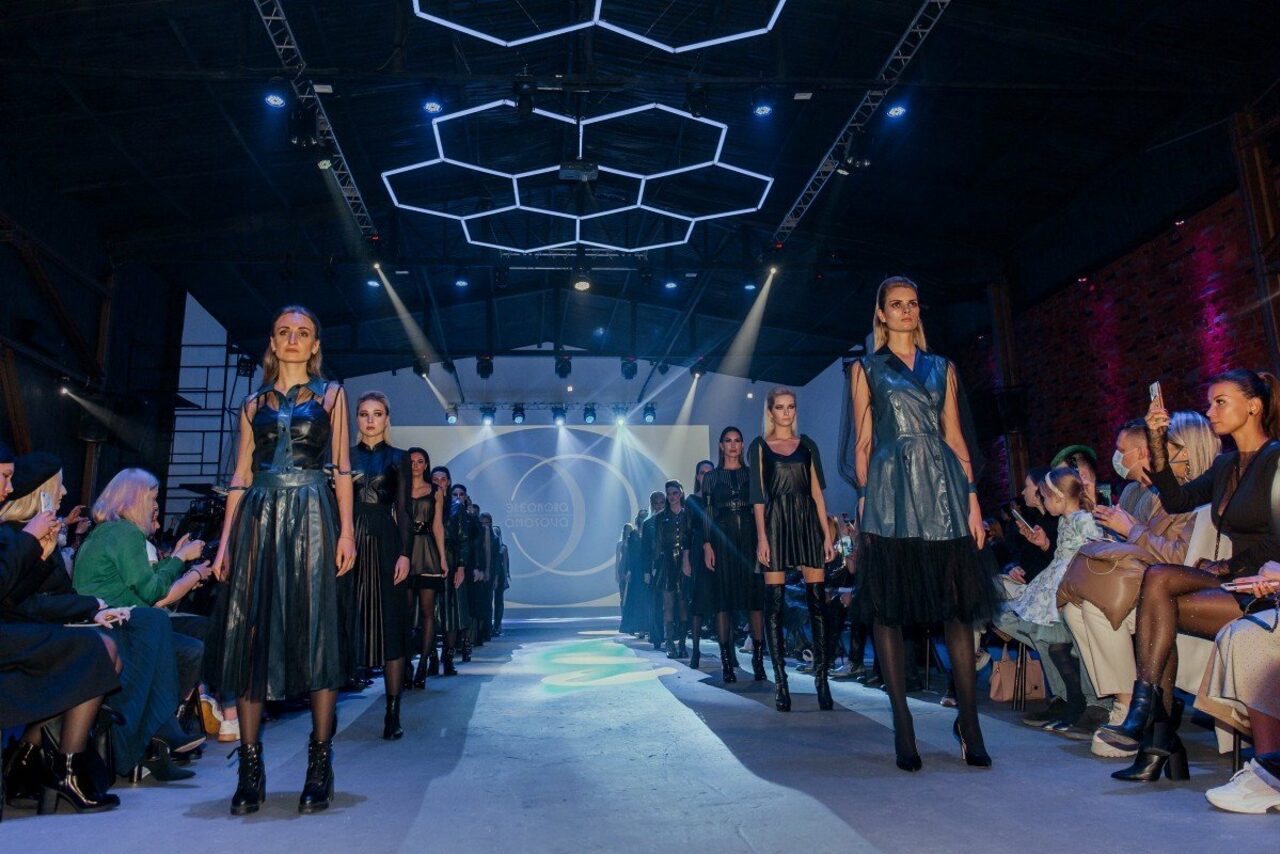 Арендовать Studio Hall(Студио Холл). Показ мод в просторном помещении с высокой потолочной конструкцией и геометрическим световым декором. Центральный подиум освещён прожекторами. С каждой стороны подиума зрители на стульях. Стены из кирпича. На заднем плане экран с визуальными проекциями.