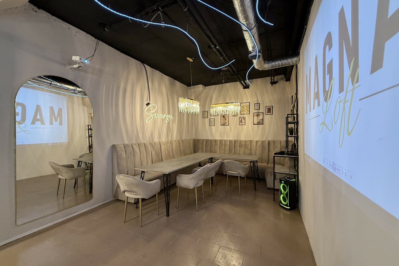 Арендовать Лофт SUNRISE(Восход Солнца). Просторное помещение на 15 гостей. Прямоугольное помещение с большим зеркалом на стене, длинным столом и стульями. Стены светлые с декоративными элементами. На потолке система освещения и вентиляции. На стенах неоновые надписи и фотографии. Проектор с изображением текста.