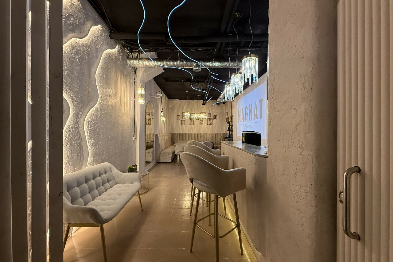 Арендовать Лофт SUNRISE(Восход Солнца). Просторное помещение на 15 гостей. Лаунж-пространство с диванами и барными стульями вдоль стены. Светлая декоративная штукатурка стен с волнистым узором, подвесные светильники и неоновая гибкая подсветка. Потолок темный с открытыми коммуникациями. На стене подсвеченный логотип.