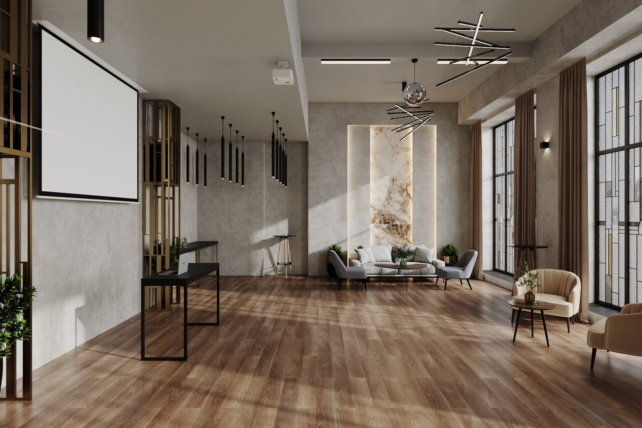 Арендовать Лофт Мираж. Просторное помещение с деревянным полом, светло-серыми стенами и большими окнами. Угловой диван с журнальным столиком, несколько стульев. Подвесные светильники, проектор и экран. Декоративные элементы, растения у стены.