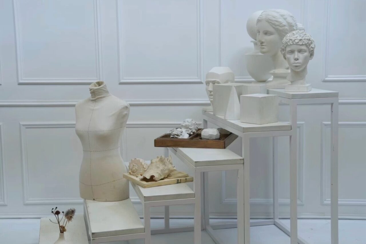 Арендовать WhiteFox Studio(Студия Белая Лиса). Пространство с белыми стенами, манекеном, статуэтками и бюстами на белых столах разной высоты. Все предметы выполнены в белых и нейтральных тонах. Состояние нового.