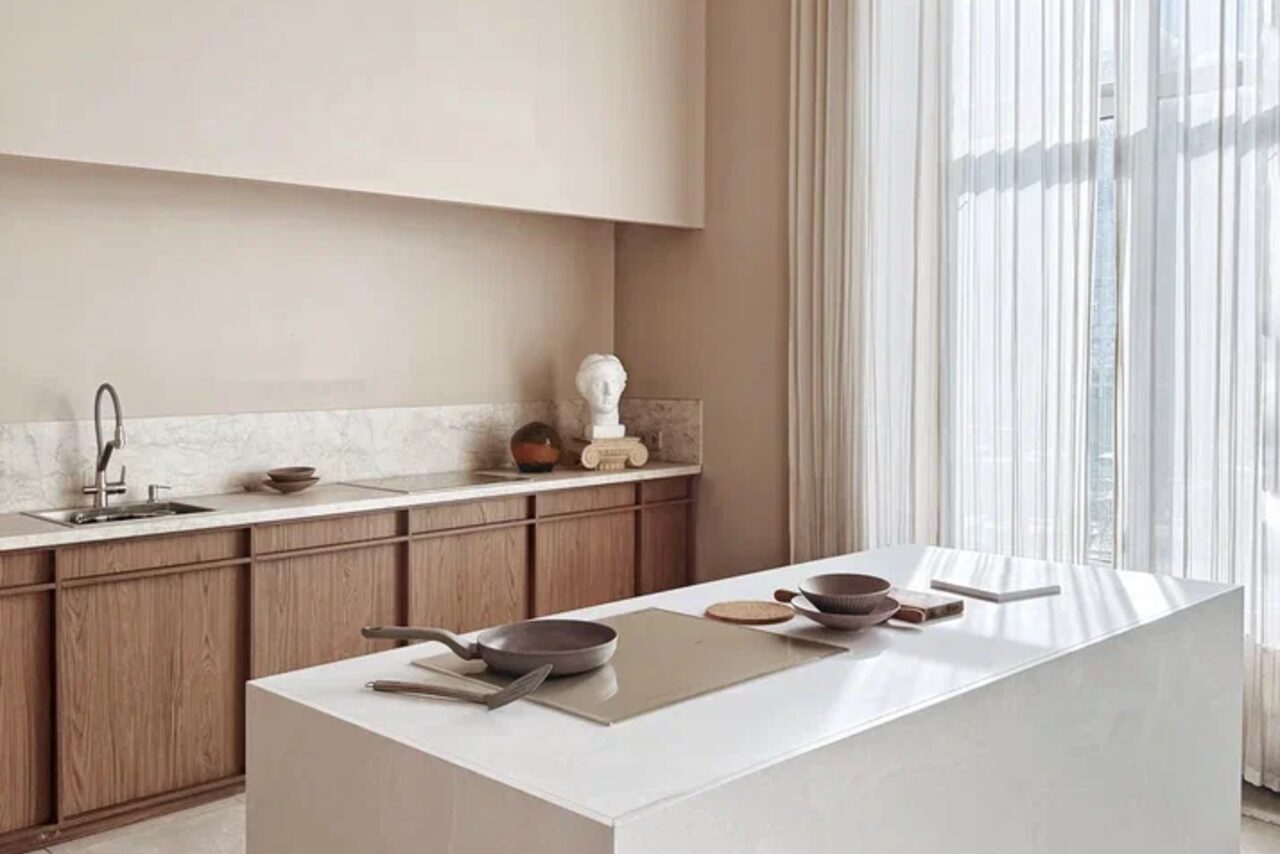 Арендовать Киото. Светлый зал с кухней. Кухонное пространство с белым островом, укомплектованным кухонной посудой. Справа раковина с краном на мраморной столешнице. Натуральное освещение через большие окна с белыми шторами. Деревянные шкафы. Стены светлого цвета. Декоративные элементы.