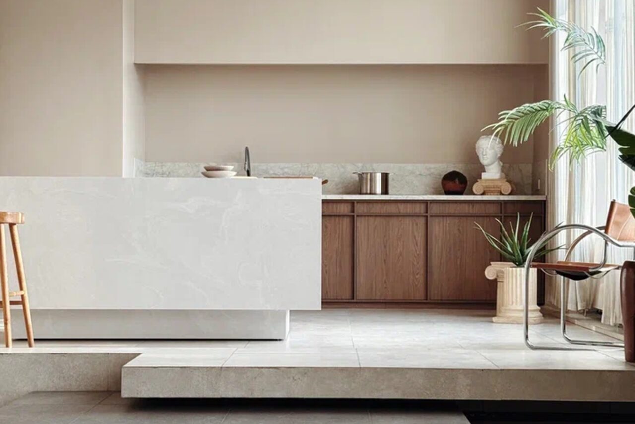 Арендовать Киото. Светлый зал с кухней. Современная кухня с островом; деревянные шкафы, мраморная столешница; высокая табуретка; декоративные растения; статуя на колонне; светлая обстановка; светлый плиточный пол; мягкое естественное освещение; бежевые и кремовые тона.