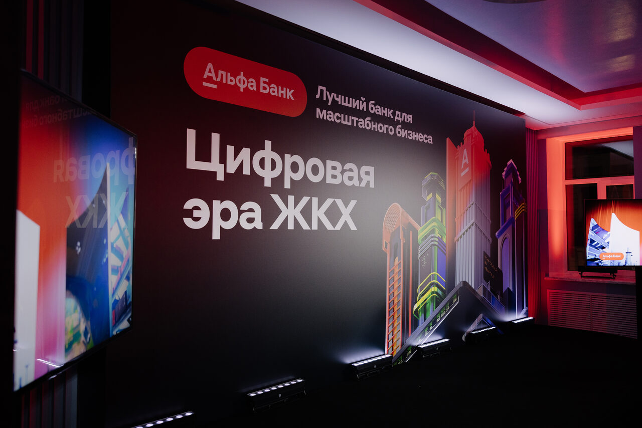 Арендовать Дом Жилищного Работника. Тип пространства: конференц-зал. Планировка: прямоугольная. Мебель/оборудование: телевизор на стене. Освещение: неоновая подсветка. Материалы: текстиль на стенах. Цвета: черный, красный, белый, разноцветные элементы. Надписи: «Цифровая эра ЖКХ», «Лучший банк для масштабного бизнеса».